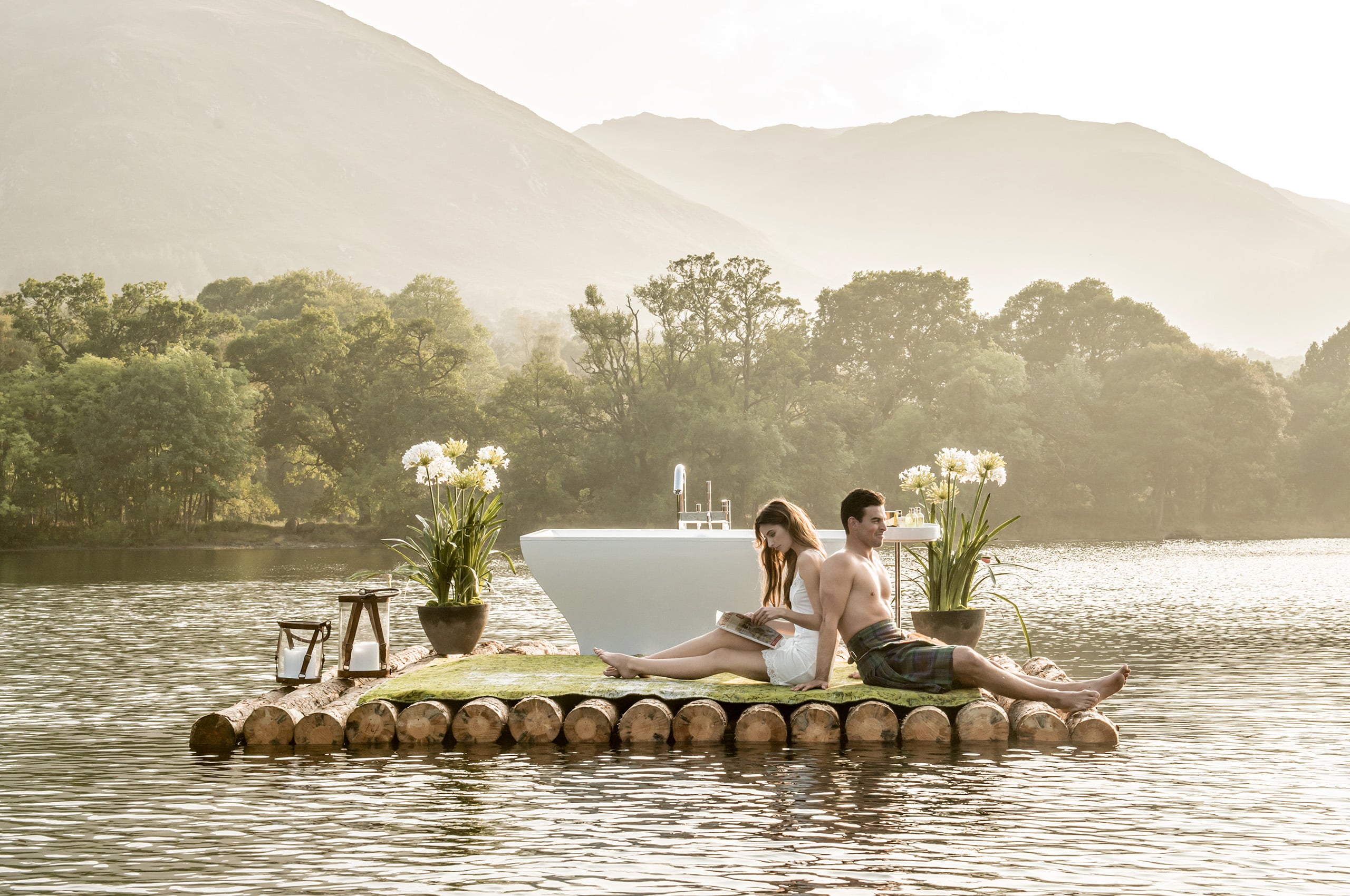 The Bathrooms Company's creative photoshoot features a lady and a guy sitting on a raft with a bath on a lake.